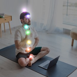 Image of Man meditating in Lotus pose at home. Rainbow lights representing chakras