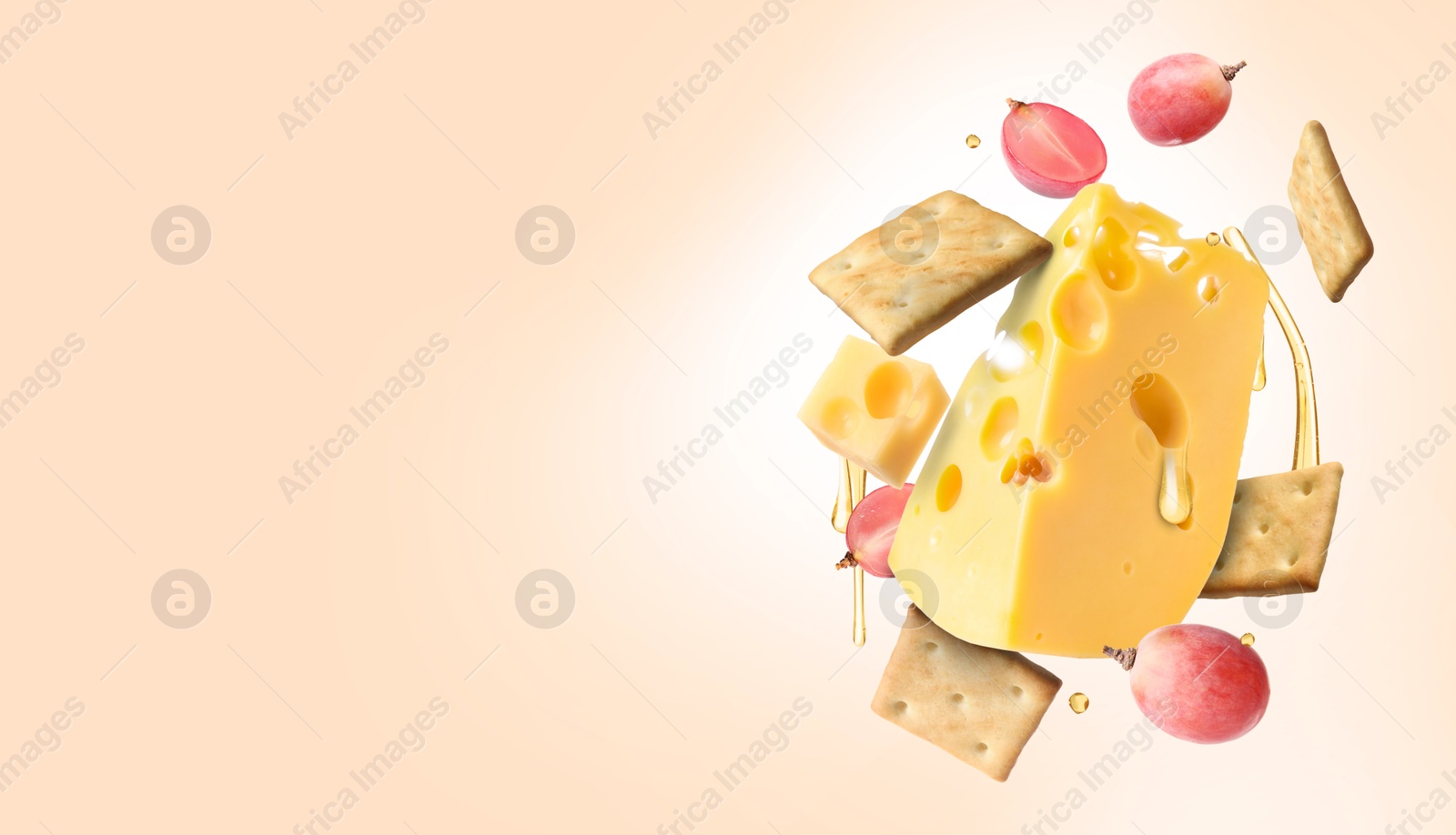 Image of Cheese, grapes, crackers and honey in air on pink beige background. Tasty appetizers for cheese board