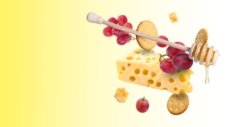 Image of Cheese, grapes, crackers and honey in air on yellow gradient background. Tasty appetizers for cheese board