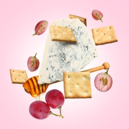Image of Cheese, grapes, crackers and honey in air on pink gradient background. Tasty appetizers for cheese board