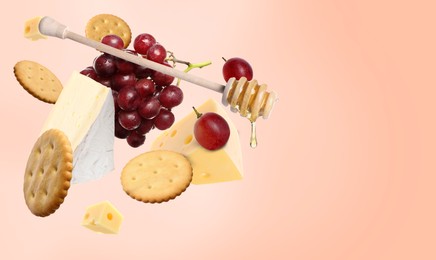 Image of Cheese board products in air on coral gradient background. Different types of cheese, grapes, crackers and honey