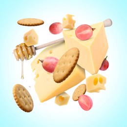 Image of Cheese board products in air on light blue background. Different types of cheese, grapes, crackers and honey