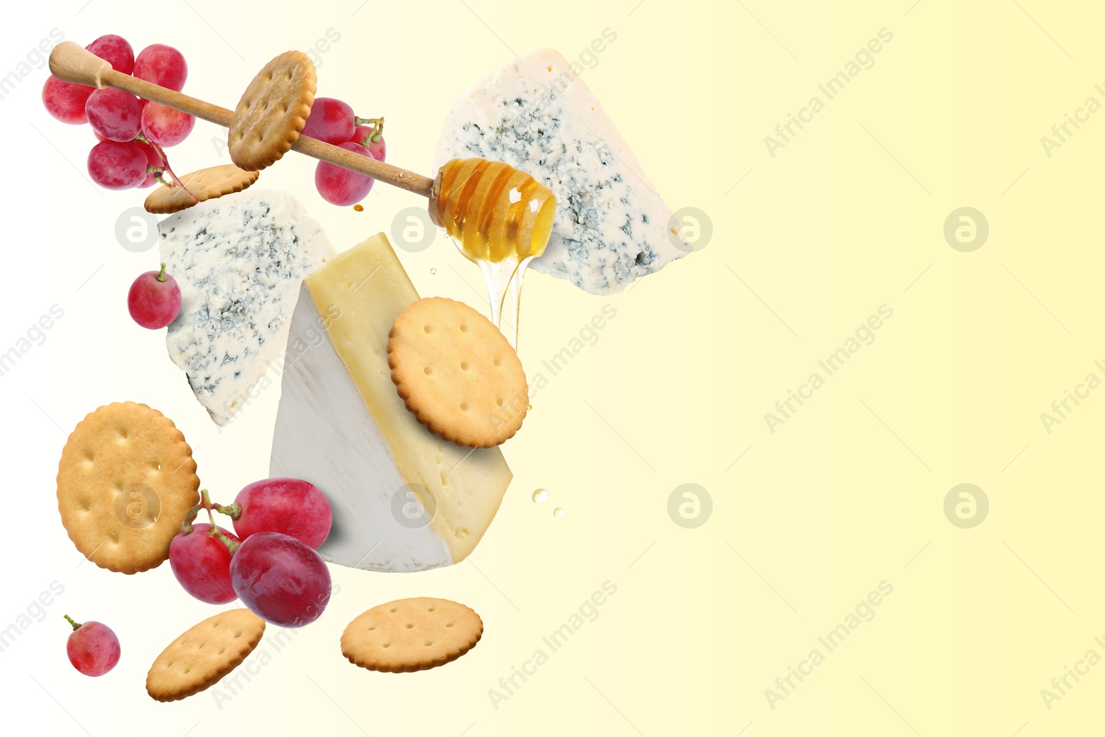 Image of Cheese board products in air on beige gradient background. Different types of cheese, grapes, crackers and honey