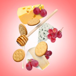 Image of Cheese board products in air on coral gradient background. Different types of cheese, grapes, crackers and honey