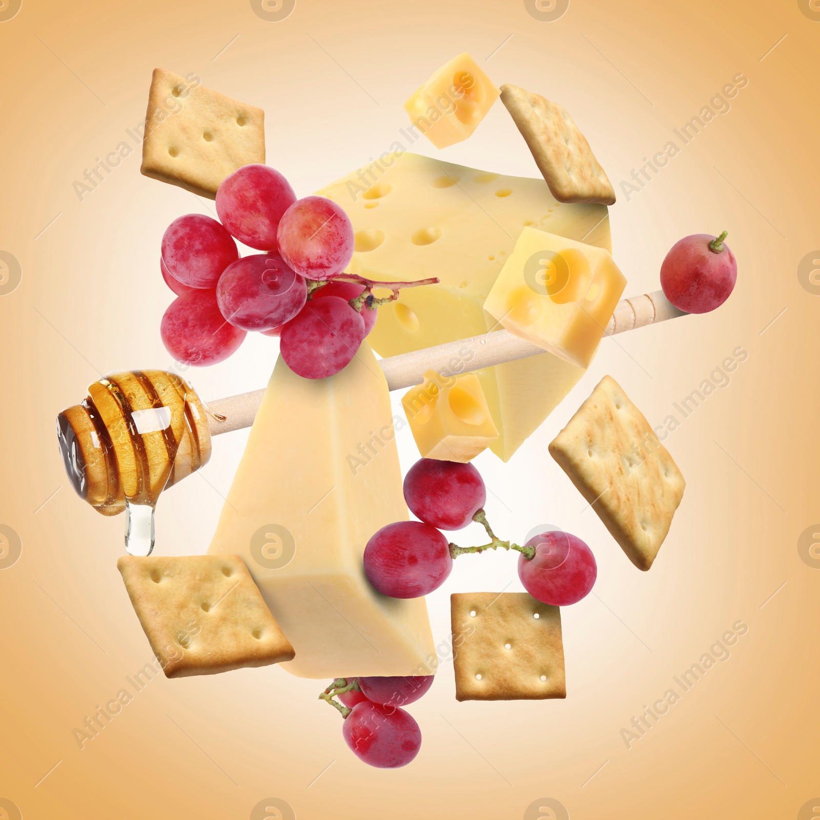 Cheese board products in air on pale orange background. Different types of cheese, grapes, crackers and honey Image of Cheese board products in air on pale orange background. Different types of cheese, grapes, crackers and honey
