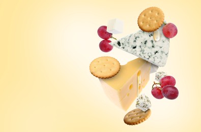 Image of Cheese board products in air on beige gradient background. Different types of cheese, grapes, crackers and honey