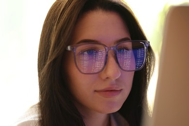 Photo of Young woman wearing glasses with reflection indoors, closeup