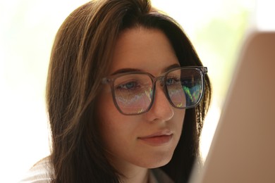 Photo of Young woman wearing glasses with reflection indoors, closeup