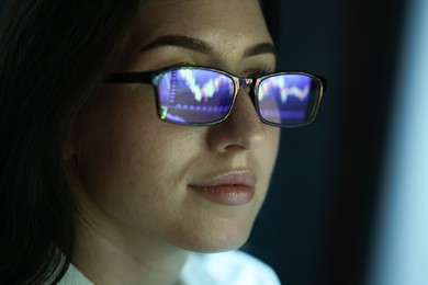 Photo of Young woman wearing glasses with reflection on dark background, closeup
