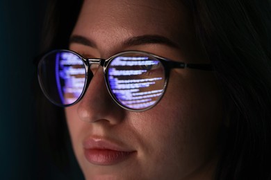 Photo of Young woman wearing glasses with reflection on dark background, closeup