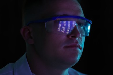 Photo of Young man wearing glasses with reflection on dark background, closeup