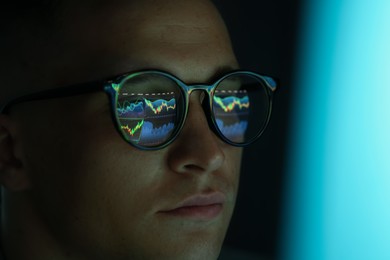 Photo of Young man wearing glasses with reflection on dark background, closeup