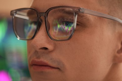 Photo of Young man wearing glasses with reflection on blurred background, closeup
