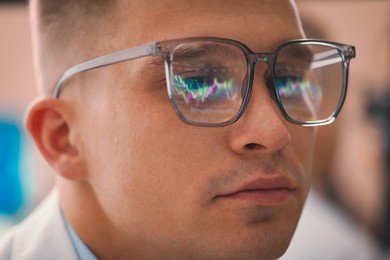 Photo of Young man wearing glasses with reflection on blurred background, closeup
