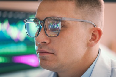 Photo of Young man wearing glasses with reflection on blurred background, closeup