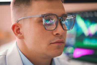 Photo of Young man wearing glasses with reflection on blurred background, closeup