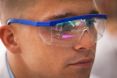 Photo of Young man wearing glasses with reflection on blurred background, closeup