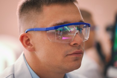 Photo of Young man wearing glasses with reflection on blurred background, closeup