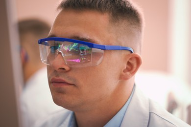 Photo of Young man wearing glasses with reflection on blurred background, closeup
