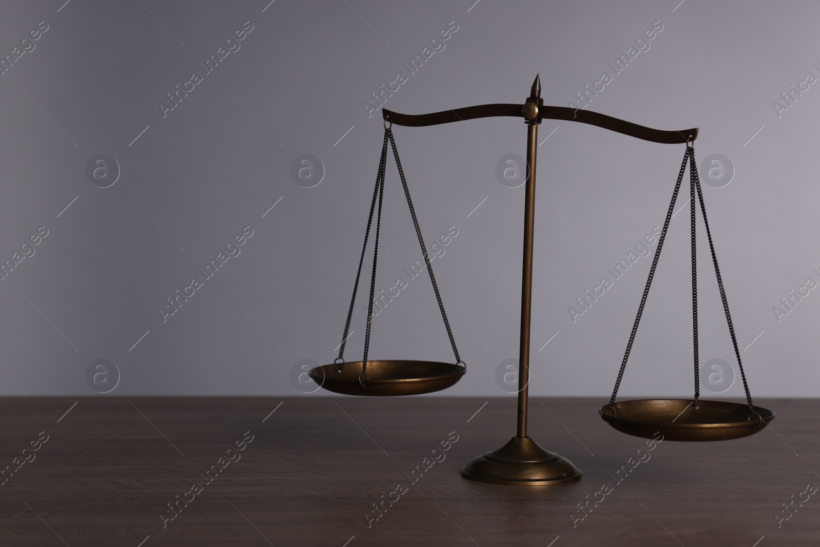 Scales of justice on wooden table against grey background. Space for text Photo of Scales of justice on wooden table against grey background. Space for text