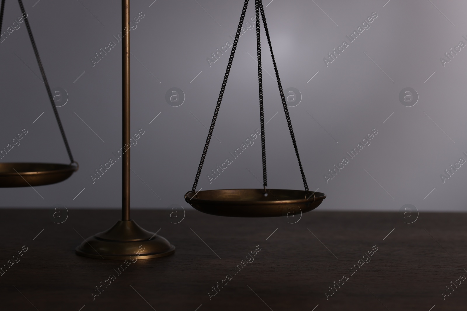 Scales of justice on wooden table against grey background, closeup Photo of Scales of justice on wooden table against grey background, closeup