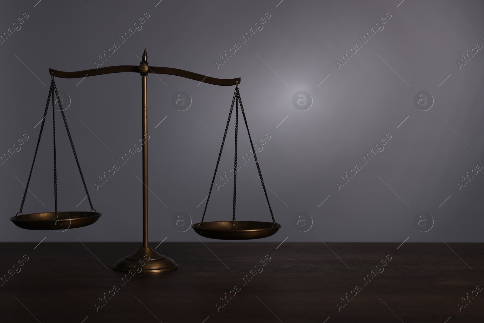 Scales of justice on wooden table against grey background. Space for text Photo of Scales of justice on wooden table against grey background. Space for text