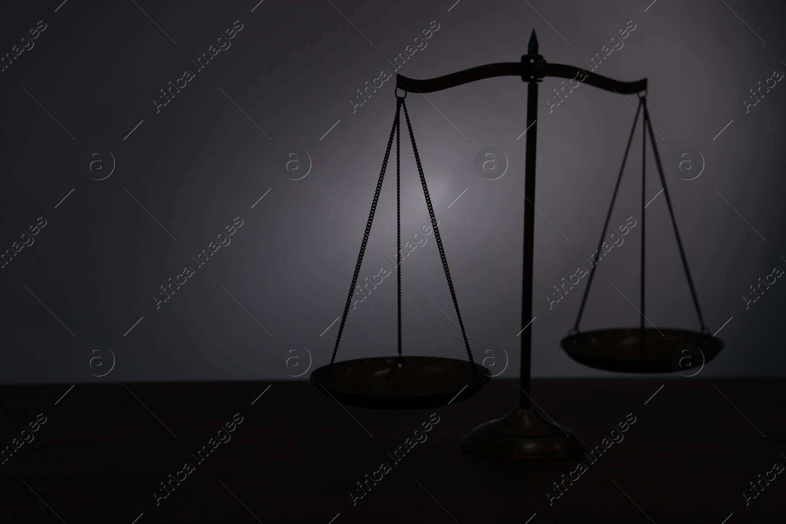 Scales of justice on table in darkness. Space for text Photo of Scales of justice on table in darkness. Space for text