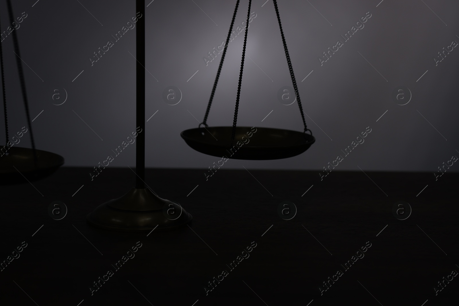 Scales of justice on table in darkness, closeup Photo of Scales of justice on table in darkness, closeup