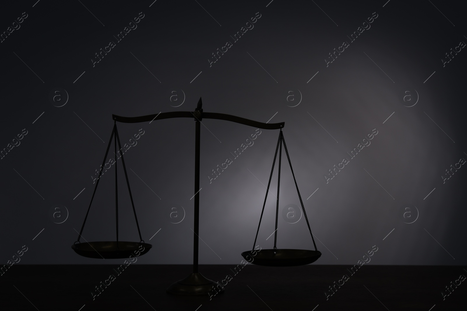 Scales of justice on table in darkness. Space for text Photo of Scales of justice on table in darkness. Space for text