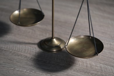 Photo of Scales of justice on wooden table, closeup