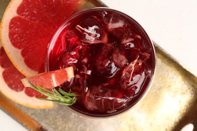 Photo of Tasty cocktail with grapefruit, ice cubes and rosemary on white table, top view