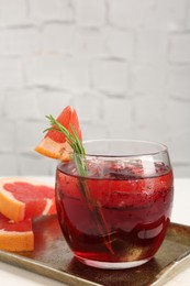 Photo of Tasty cocktail with grapefruit, ice cubes and rosemary on white table, closeup