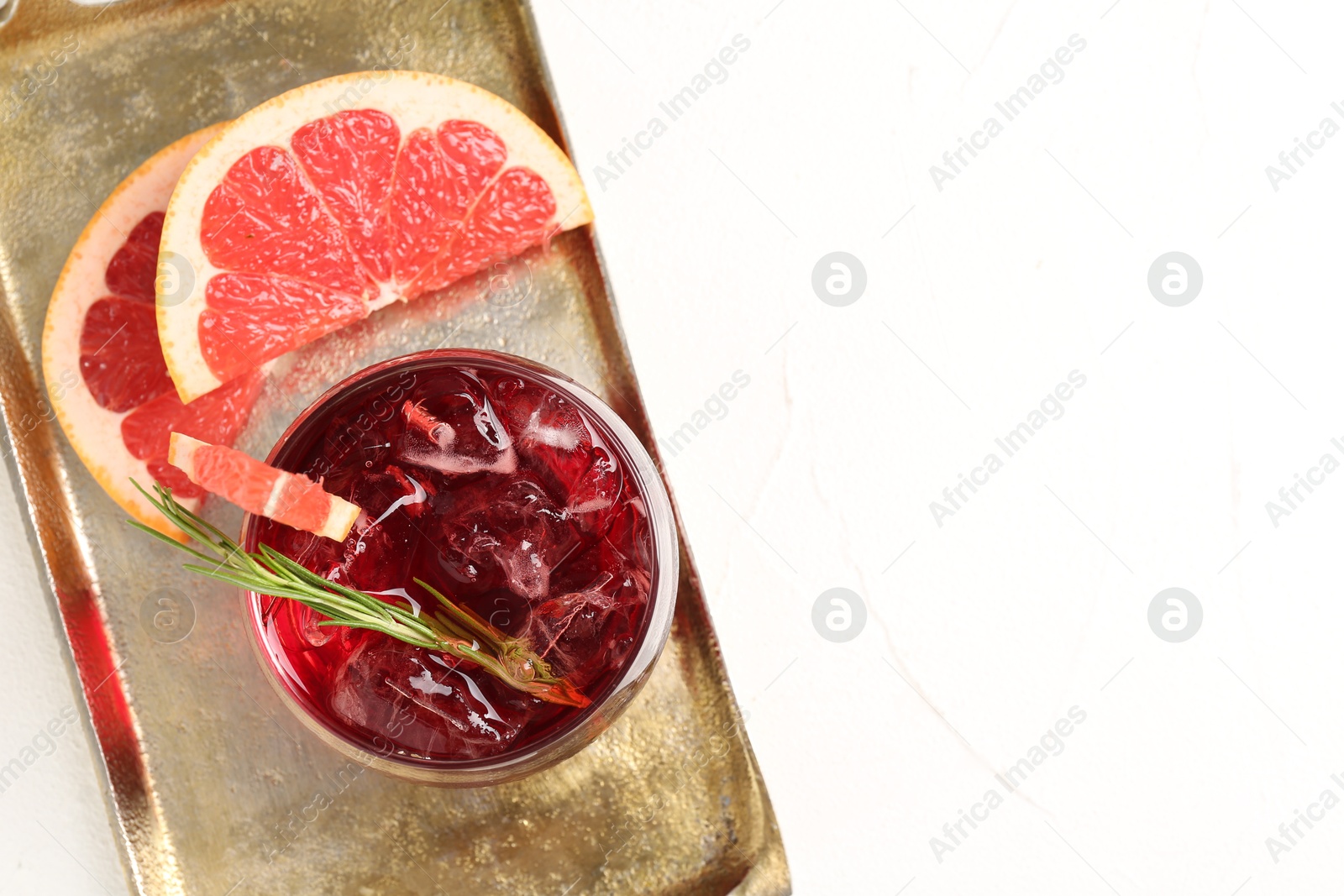 Photo of Tasty cocktail with grapefruit, ice cubes and rosemary on white table, top view. Space for text