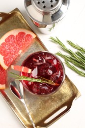 Photo of Tasty cocktail with grapefruit, ice cubes, rosemary and shaker on white table, flat lay
