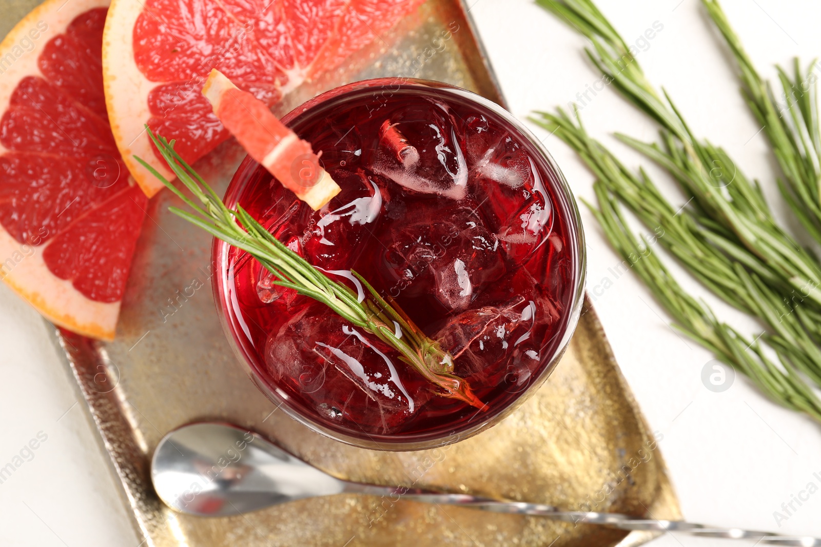 Photo of Tasty cocktail with grapefruit, ice cubes and rosemary on white table, flat lay