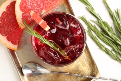 Photo of Tasty cocktail with grapefruit, ice cubes and rosemary on white table, flat lay
