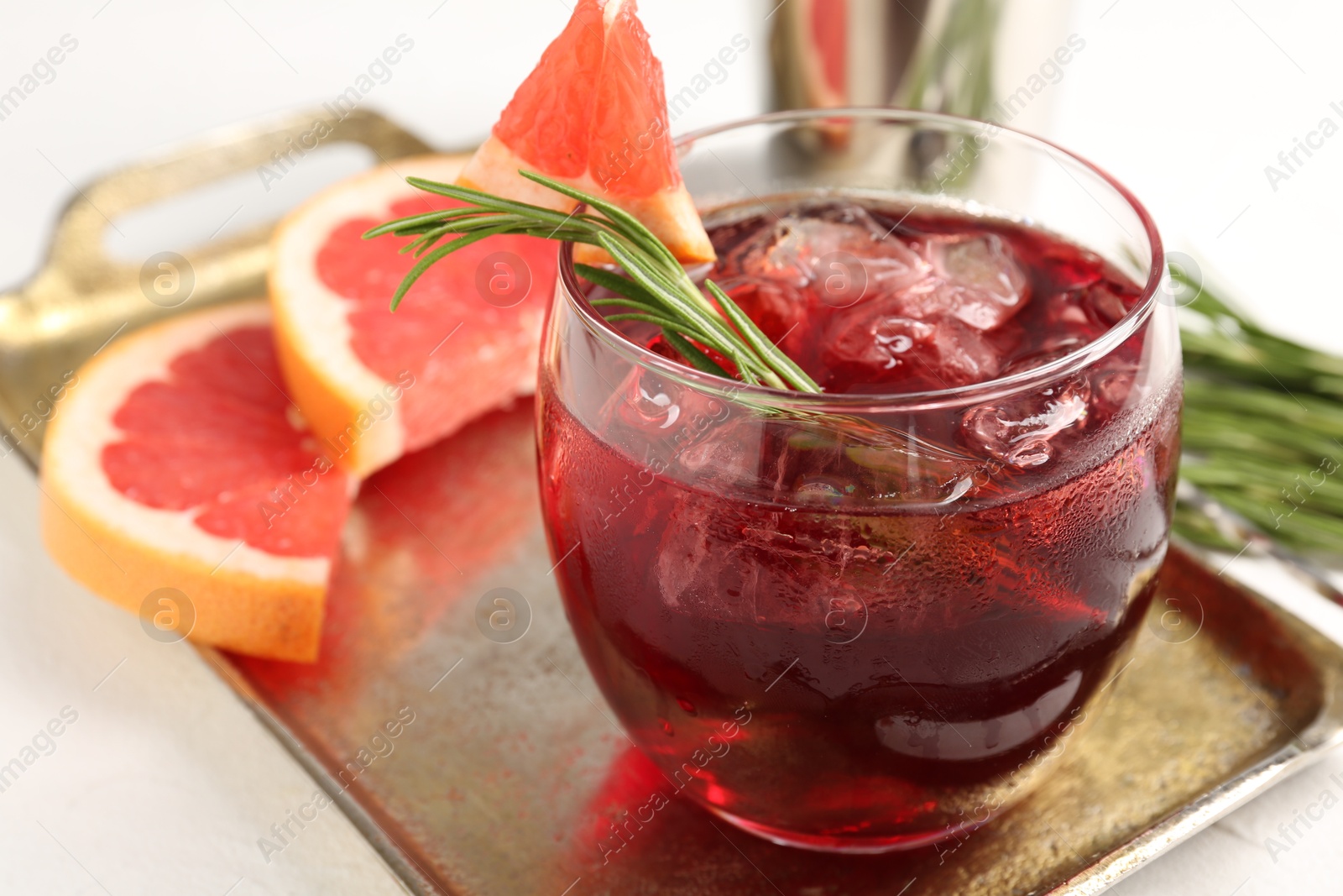 Photo of Tasty cocktail with grapefruit, ice cubes and rosemary on white table, closeup