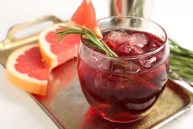 Photo of Tasty cocktail with grapefruit, ice cubes and rosemary on white table, closeup