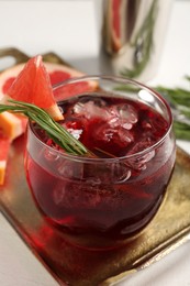 Photo of Tasty cocktail with grapefruit, ice cubes and rosemary on white table, closeup