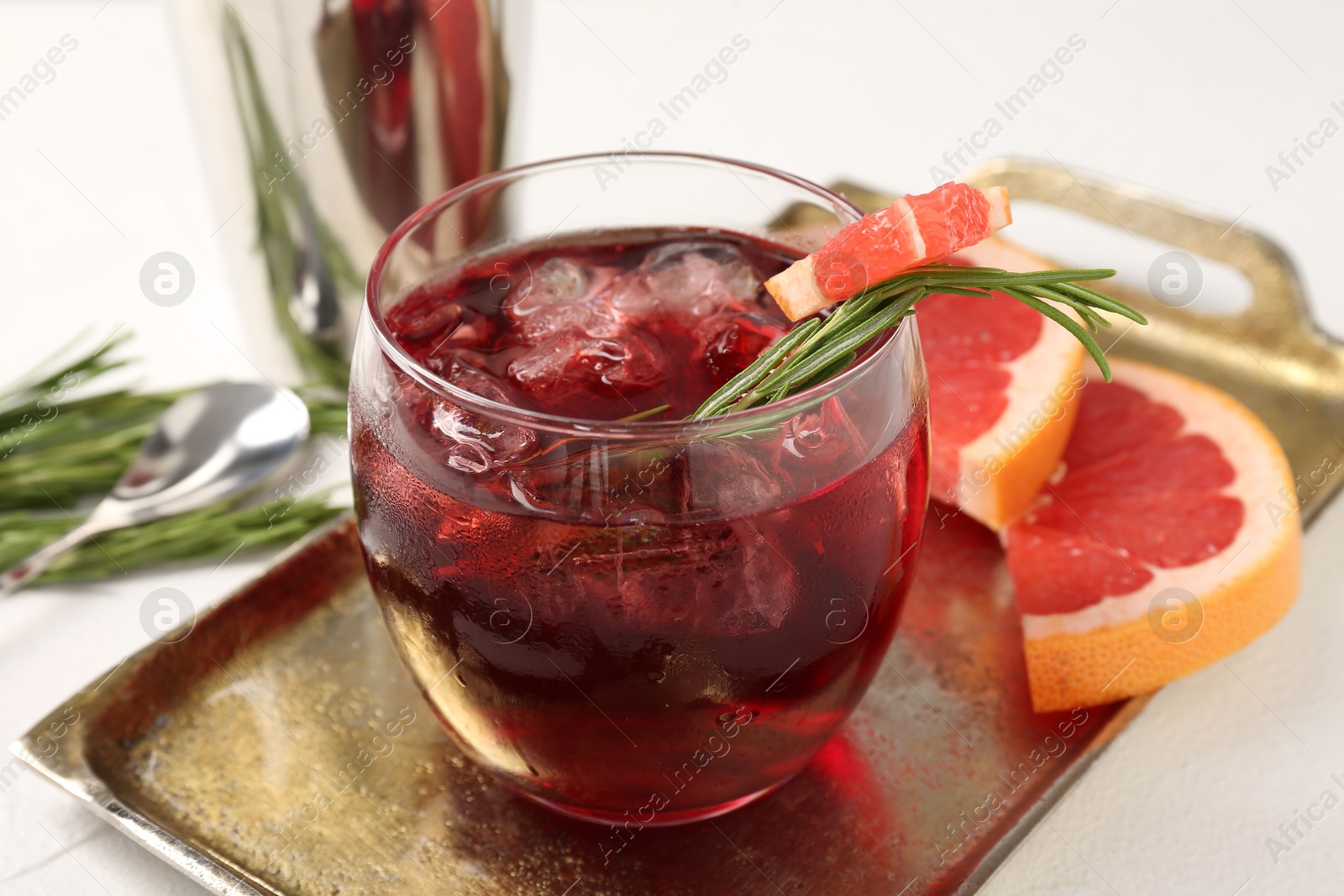 Photo of Tasty cocktail with grapefruit, ice cubes and rosemary on white table, closeup