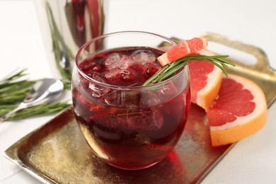 Photo of Tasty cocktail with grapefruit, ice cubes and rosemary on white table, closeup