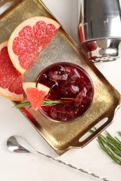 Photo of Tasty cocktail with grapefruit, ice cubes, rosemary and shaker on white table, flat lay