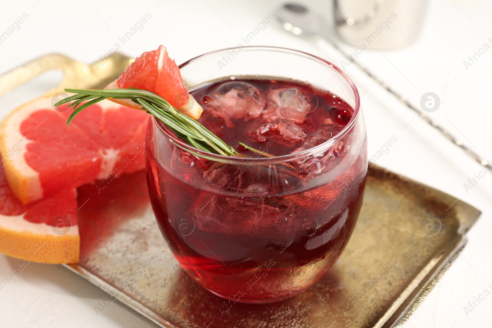 Photo of Tasty cocktail with grapefruit, ice cubes and rosemary on white table, closeup