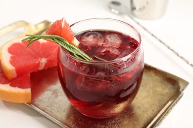 Photo of Tasty cocktail with grapefruit, ice cubes and rosemary on white table, closeup