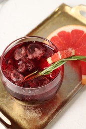 Photo of Tasty cocktail with grapefruit, ice cubes and rosemary on white table, closeup