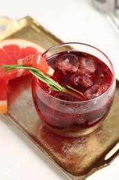 Photo of Tasty cocktail with grapefruit, ice cubes and rosemary on white table, closeup