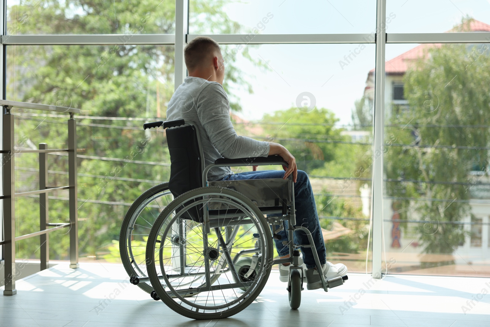 Young man in wheelchair near window indoors Photo of Young man in wheelchair near window indoors