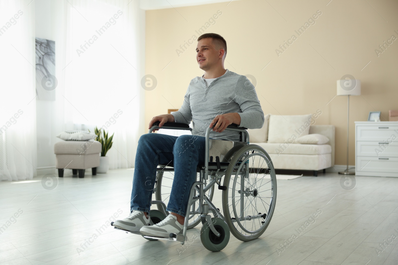 Photo of Young man in modern wheelchair at home