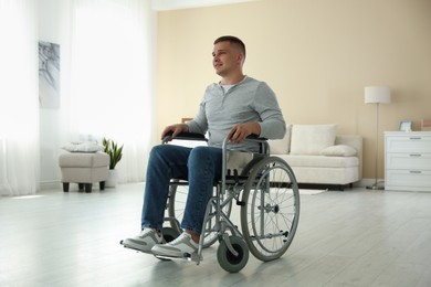 Photo of Young man in modern wheelchair at home