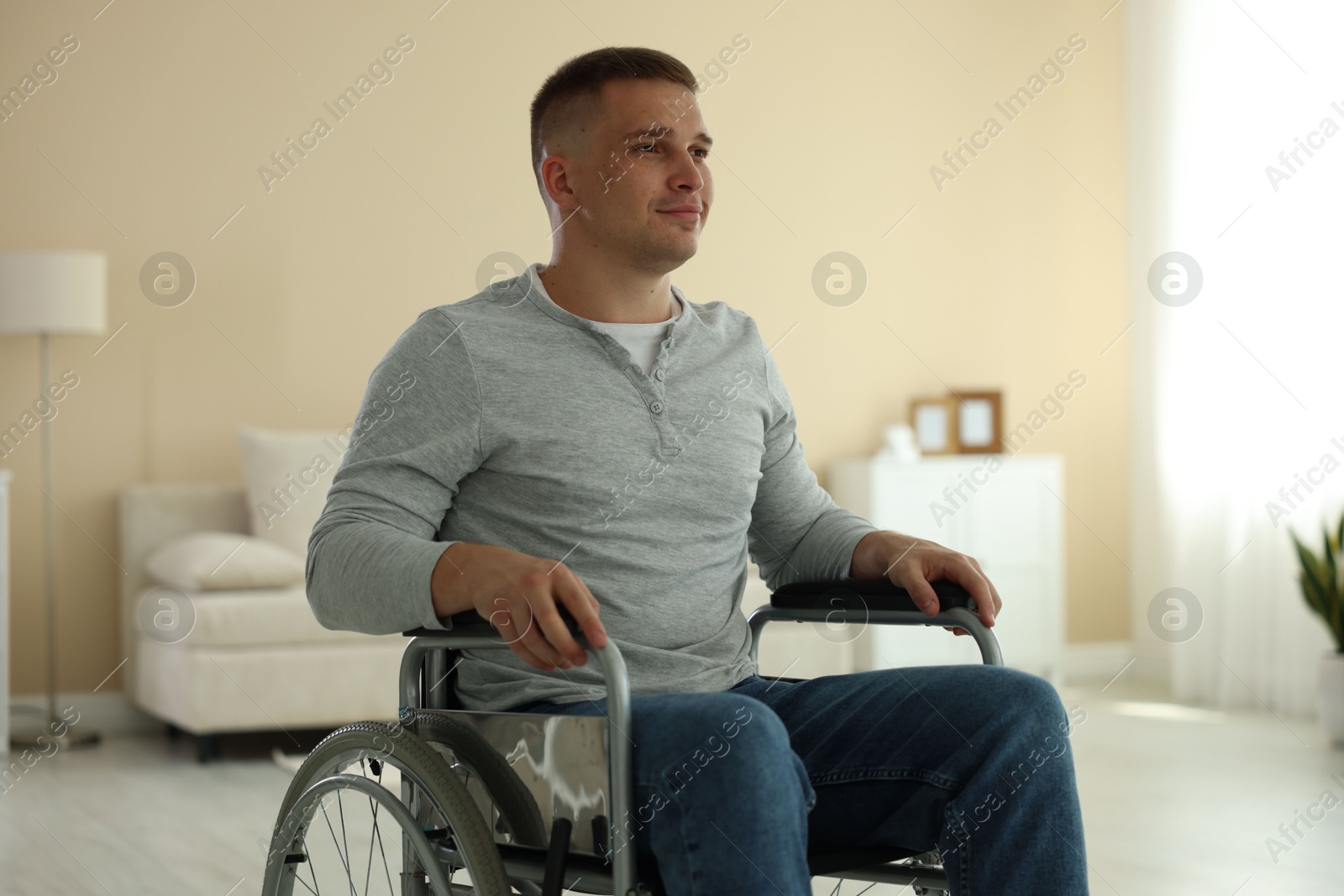 Young man in modern wheelchair at home Photo of Young man in modern wheelchair at home